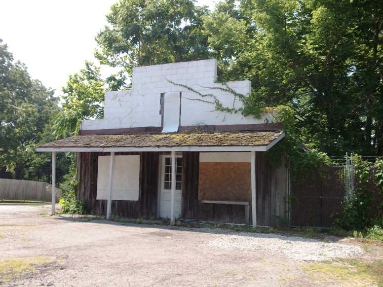 An abandoned building with a rotting siding and a roof.
